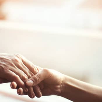 Young person holding the hand of an elderly person in a caring way