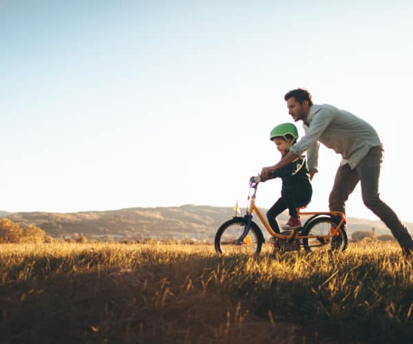 Father teaching his son how to ride his bike.