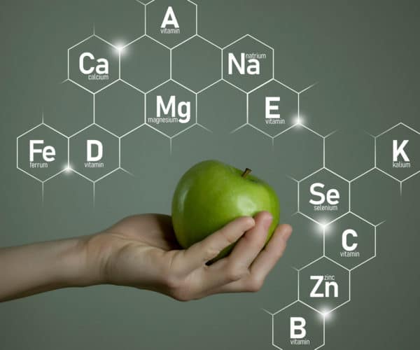 Person holding an apple with periodic table elements in the background