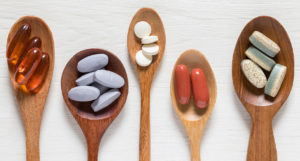 Wooden spoons holding different amounts of vitamins and supplements on a table