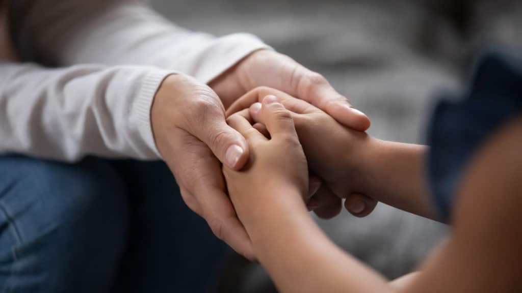 Person holding another persons clasped hands