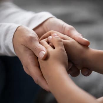 Person holding another persons clasped hands