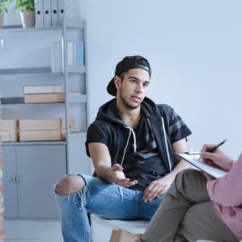 A rebel teenage boy with a drug addiction talking to a psychotherapist.