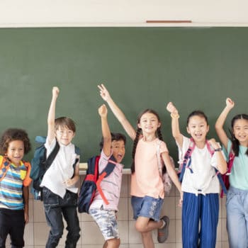 Group of diverse young students standing together in classroom smiling and happy