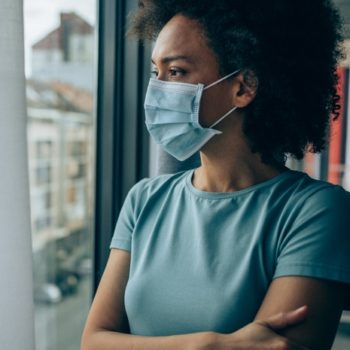 Woman wearing mask looking through window