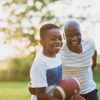 Father and son playing football outside.