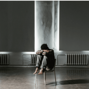 schizophrenic man sitting alone in a dark room with head buried in arms