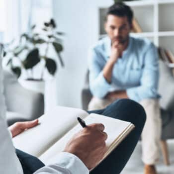 Young frustrated man solving his mental problems while having therapy session with psychologist